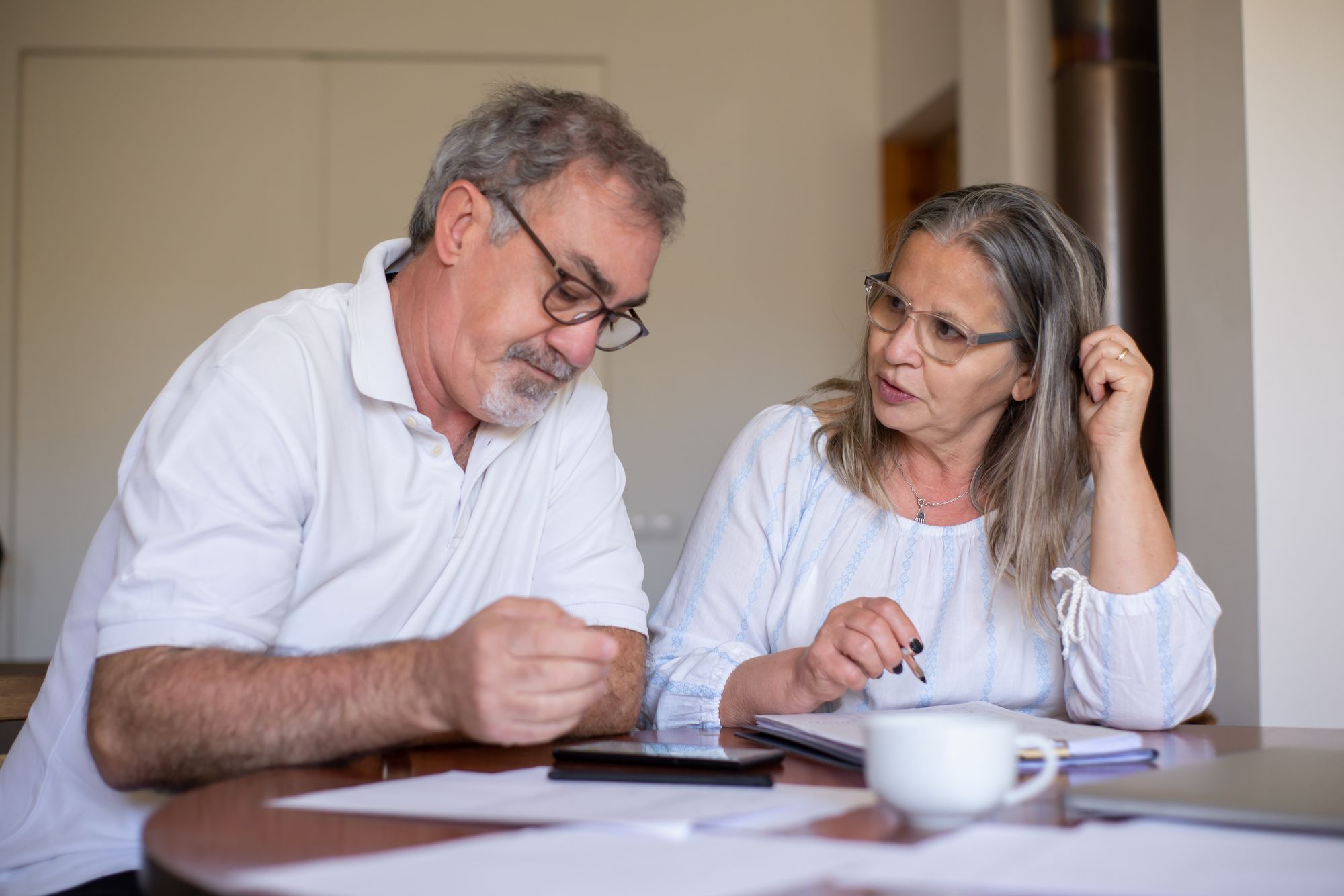 A mature couple reviewing paperwork together at home; illustrative stock photograph.