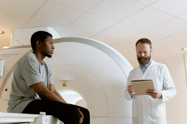 A medical professional reviewing records beside a seated adult and a scanner; illustrative stock photograph.